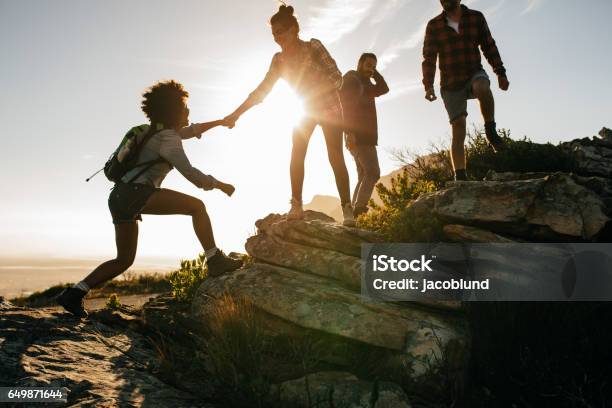 Caminata De Jóvenes En La Montaña Al Atardecer Foto de stock y más banco de imágenes de Excursionismo - Excursionismo, Personas, Grupo de personas