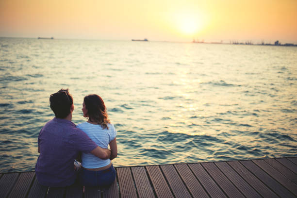 Young couple watching sunset on the pier