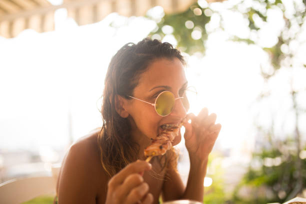 Young woman at the beach restaurant eating souvlaki with her hands