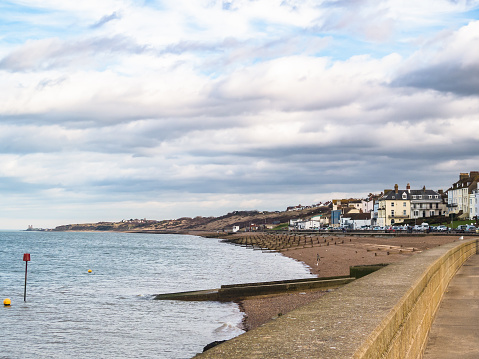 The coastline looking towards Reculver Towers of Herne Bay, Kent, UK. The pebble beach has water breakers, groynes protecting the beach.