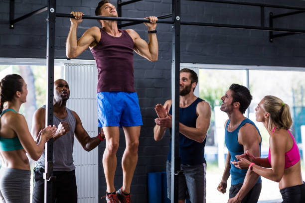 istock Friends cheering young man doing chin-ups 649883356