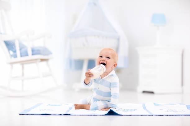 istock Baby boy drinking milk in sunny nursery 649898190