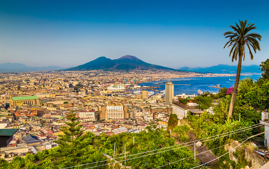 Scenic picture-postcard view of the city of Napoli (Naples) with famous Mount Vesuvius in the background in golden evening light at sunset, Campania, Italy