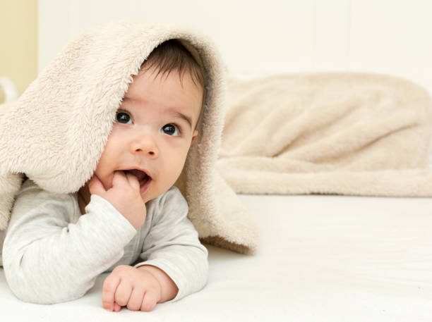 Cute baby boy in bed under a fluffy blanket stock photo