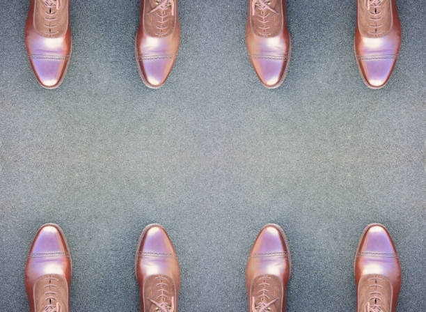 Legs of five friends in different shoes standing together, top view