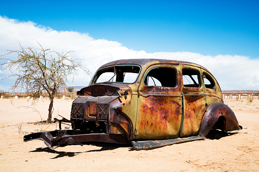 A rusty, abandoned, vintage American car in the desert, Namibia.