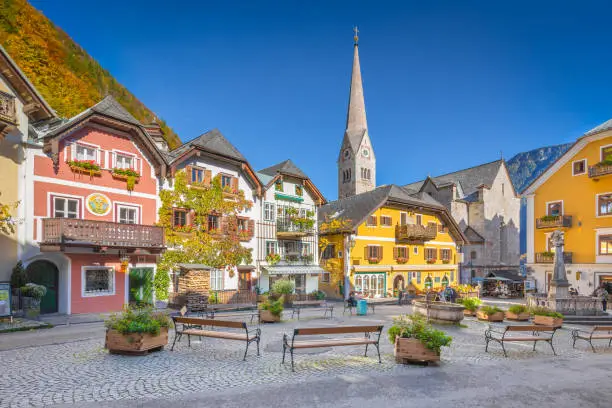 Scenic picture-postcard view of the historic town square of Hallstatt with traditional colorful houses and church at Hallstatter See in the Austrian Alps in fall, region of Salzkammergut, Austria