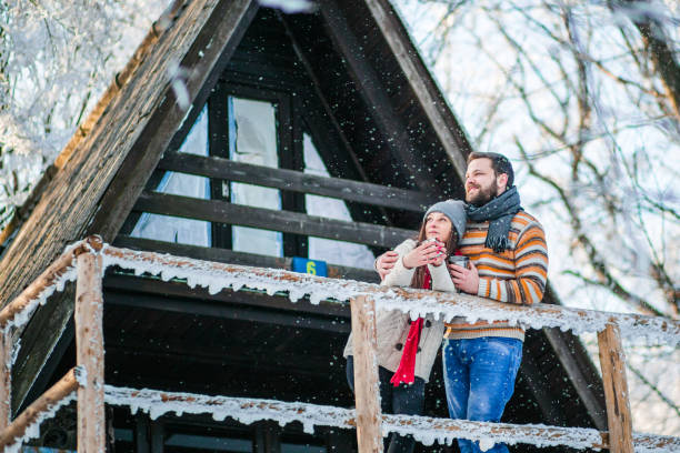 молодая пара перед бревенчатой хижиной - transportation mountain winter couple стоковые фото и изображения