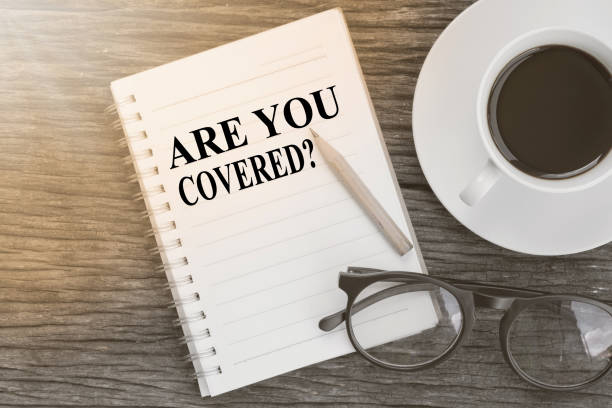 istock Concept Are you covered? message on notebook with glasses, pencil and coffee cup on wooden table. 649944940