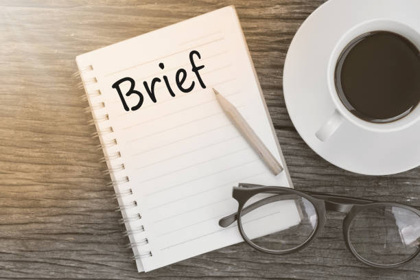 istock Concept Brief on notebook with glasses, pencil and coffee cup on wooden table. 649944970