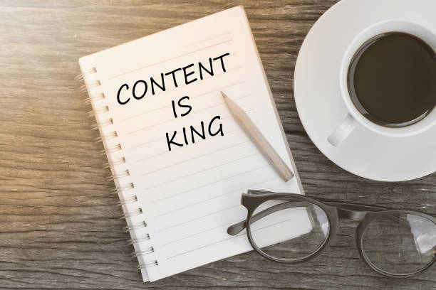 istock Content is King text on notebook with coffee cup, glasses and pencil on wooden background 649944972