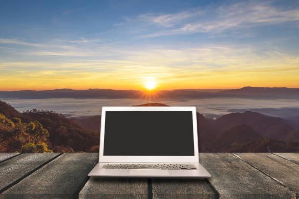 istock Laptop with blank screen on wooden table with forest in mountain and pine trees background, can used for display or montage your products 649960000