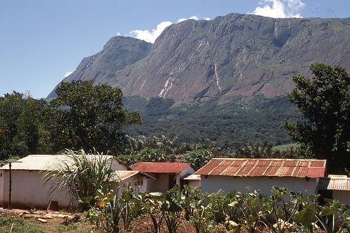 Mulanje Massif with steep cliffs and waterfalls along edges rising above village in southern Malawi Africa