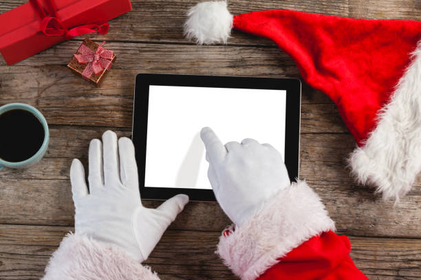 istock Santa claus using digital tablet on wooden plank 649987236