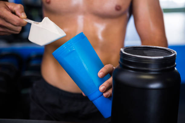 istock Shirtless athlete adding nutritional supplement in water 649987530