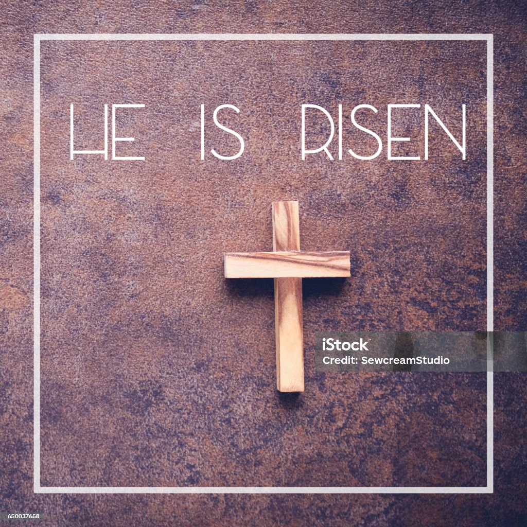 He is risen word and wooden cross on dark background Australia Stock Photo