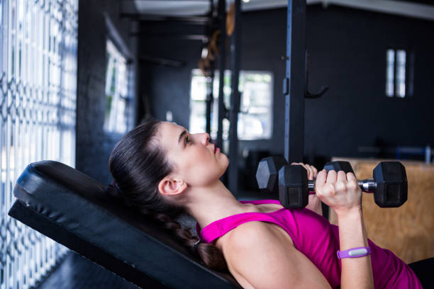 istock Female athlete holding dumbbell while lying on bench press 650043846