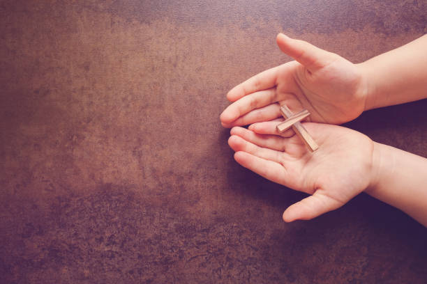 cruz de madera en orando las manos de los niños, copia espacio oscuro tono de fondo - praying human hand worshipper wood fotografías e imágenes de stock