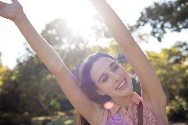 istock Happy woman standing in the park with her hands raised 650060124
