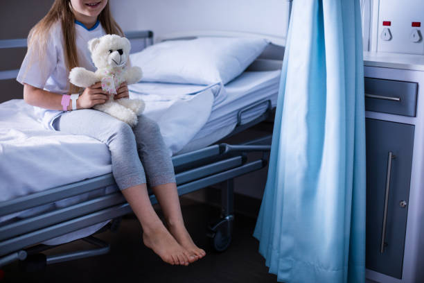 istock Patient sitting with teddy bear on hospital bed 650090608