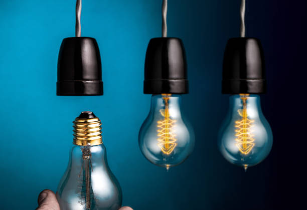 istock Hand changing a antique edison style filament light bulbs on dark blue background. 650099632