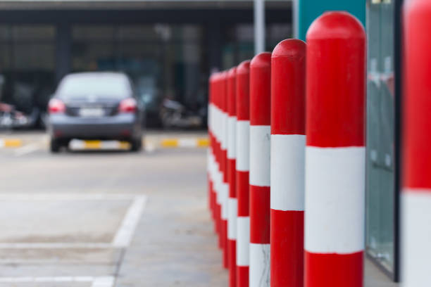 Two poles with red and white stripes are on the sidewalk. One pole is on the left side of the other pole