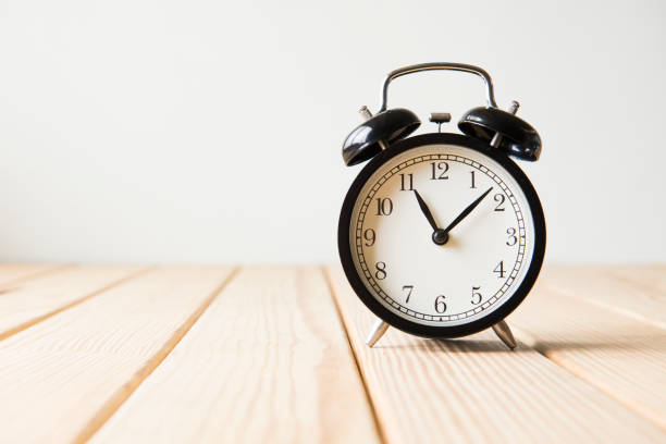 istock Clock on the wooden table on white background 650151538