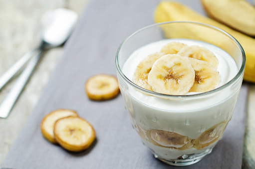 Greek yogurt banana parfait on a wood background. toning. selective focus