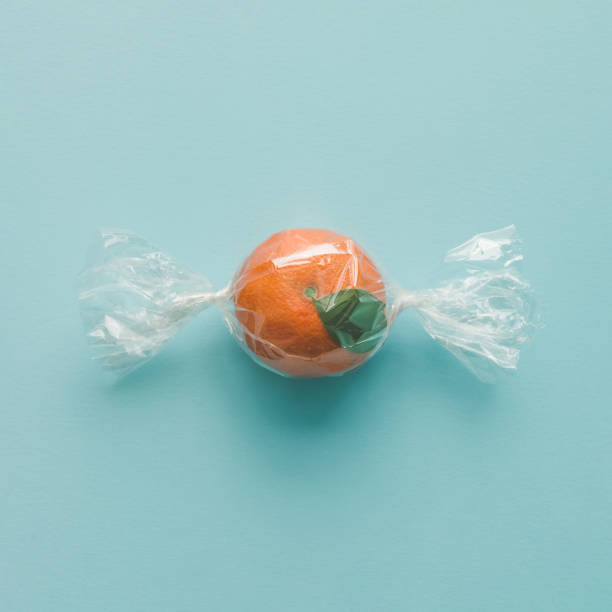 istock Orange wrapped like candy on bright blue background. minimal food concept. 650176344