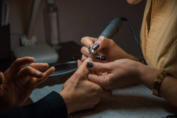 istock Manicurist makes manicure procedure with a machine on manicure table, two females 650189996