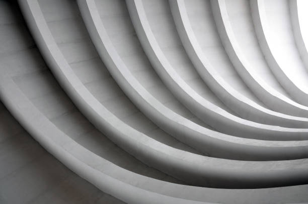 Architectural background. Modern white concrete arched composition of city bridge in perspective. Semicircular shapes. The light in the end.