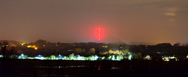 Broadcasting tower photographed at night on the Isle of Wight, with street lights illuminating a road in the foreground.