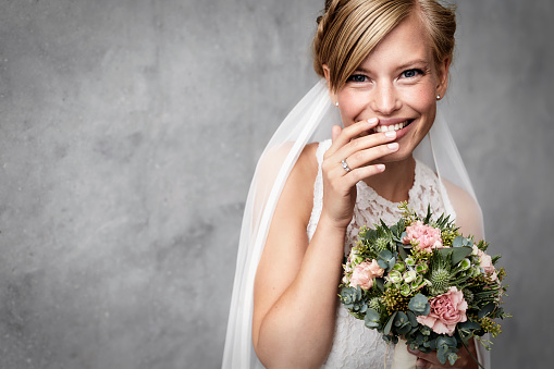 Shy bride holding flowers in studio