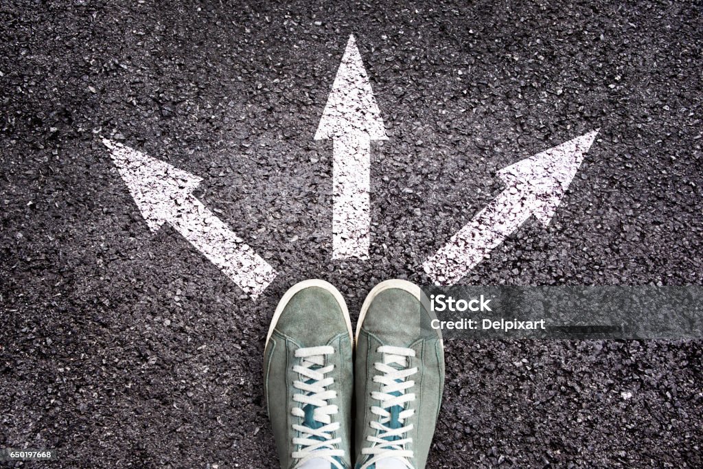 Chaussures et flèches pointant dans des directions différentes sur le plancher de l’asphalte - Photo de Choix libre de droits