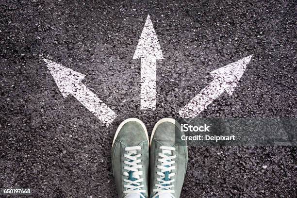 Shoes And Arrows Pointing In Different Directions On Asphalt Floor Stock Photo - Download Image Now