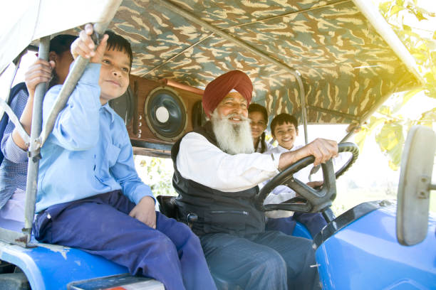 istock Old man with grand children riding tractor 650205588