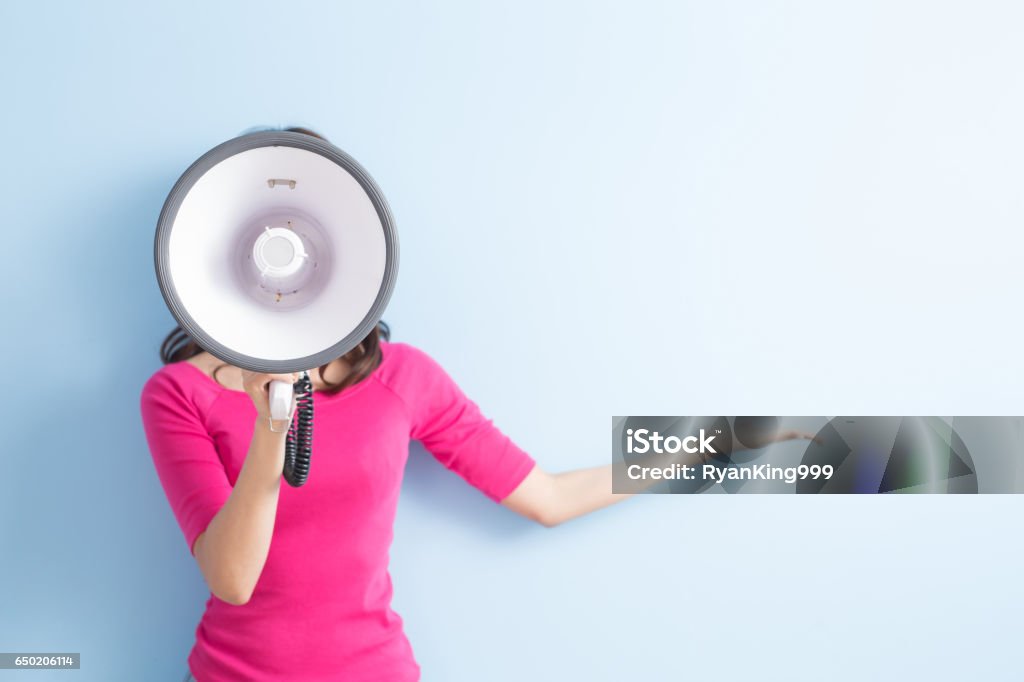 woman take microphone woman take microphone and show something to you isolated on blue background Megaphone Stock Photo