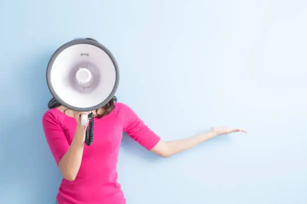 woman take microphone and show something to you isolated on blue background