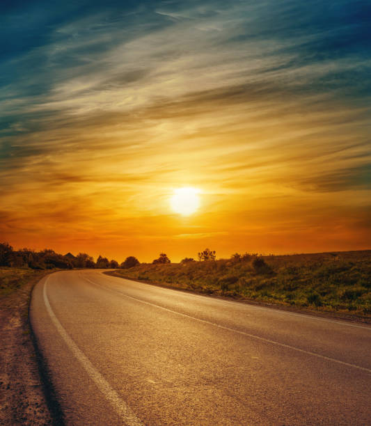 istock asphalt road to horizon and low sun in dramatic clouds 650206128