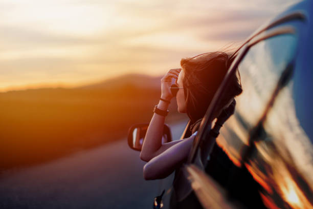 Beauty in time of sunset Beautiful young woman sitting in the car on the country road  and looking at the view on a beautiful sunny spring day driving photos stock pictures, royalty-free photos & images