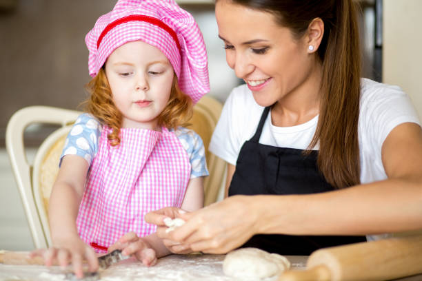 istock Smiling woman making cookie with little daughter 650218912