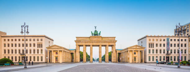 architecture, berlin, berlin wall, berliner, berliner mauer, blue sky, boulevard, brandenburg gate, brandenburger tor, building, capital, city, cityscape, cobblestone, column, downtown, east berlin, europe, german, germany, historic, holidays, monument, n Panoramic view of famous Brandenburger Tor (Brandenburg Gate), one of the best-known landmarks and national symbols of Germany, in beautiful golden morning light at sunrise, Pariser Platz, Berlin, Germany east berlin photos stock pictures, royalty-free photos & images