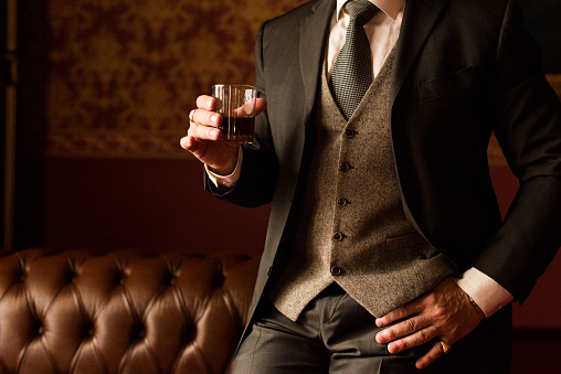 Novio elegante sostiene en su mano un vaso de whisky photo