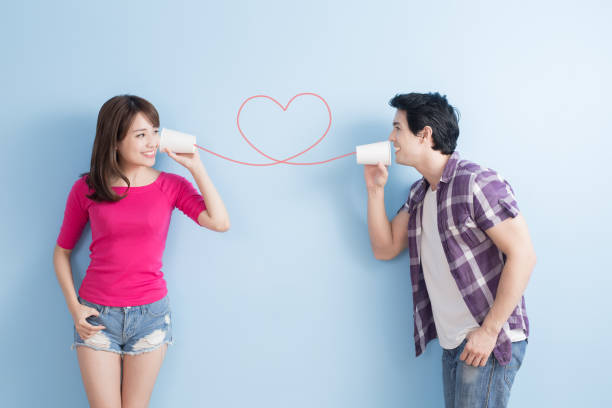 jovem casal com telefone - whispering couple discussion smiling - fotografias e filmes do acervo