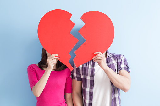 young couple take broken heart isolated on blue background