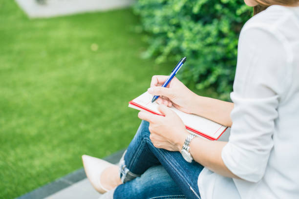 istock student writing at park, working outdoor women work business job writer write text in notebook. 650250614