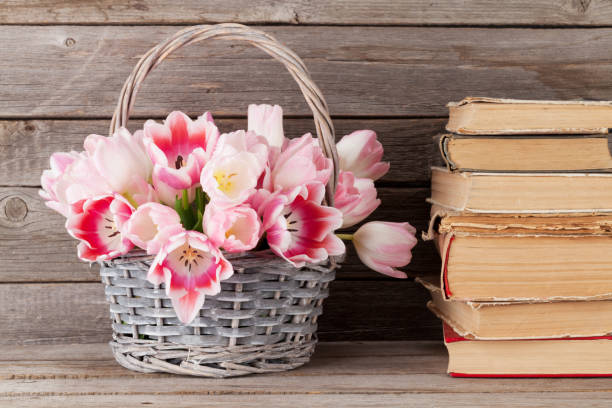 istock Pink tulips bouquet basket and old books 650250996