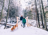 Father and son walk with dog in snow forest