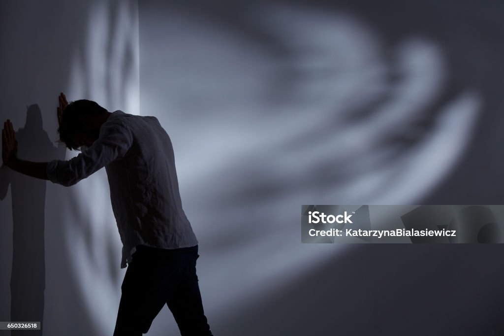 Man punching the wall Stressed man punching the wall, standing at dark room Adult Stock Photo