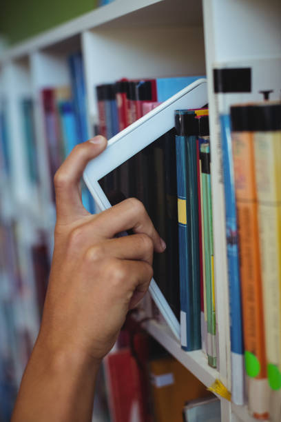 istock Hand of student keeping digital tablet in bookshelf in library 650326850